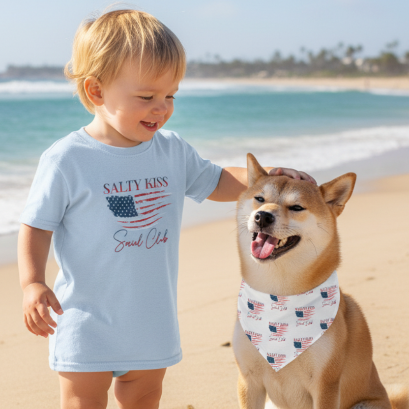 Toddler wearing USA t-shirt with dog in USA bandana at beach